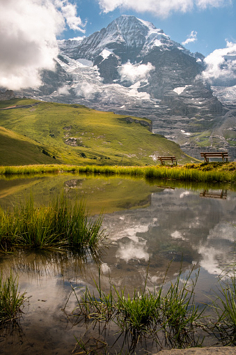 Scenic view on majestic mountain Mönch and the reflection in a small alpine lake high up in the Bernese Alps in the summer. Jungfrau Region, Bernese Oberland, Switzerland
