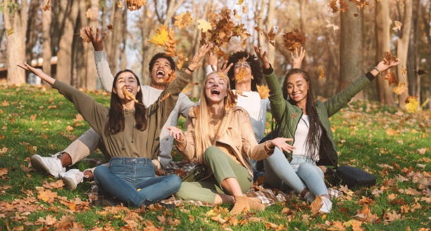 istock Happy students playing with golden leaves in park 1270416918