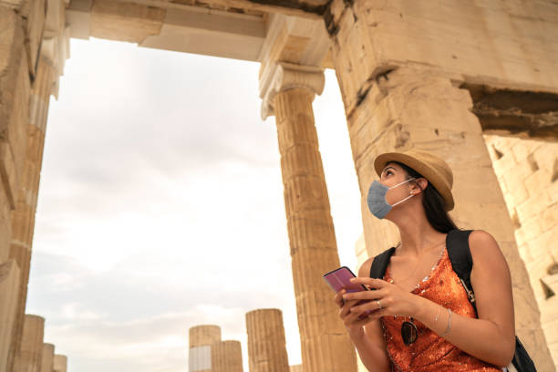 Tourist using face mask and using smartphone visiting ancient greek city Tourist using face mask and using smartphone visiting ancient greek city parthenon athens photos stock pictures, royalty-free photos & images