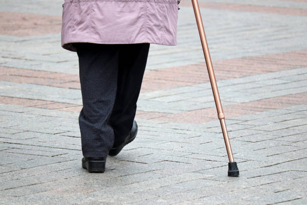 istock Limping woman walking with a cane down the street 1270418744