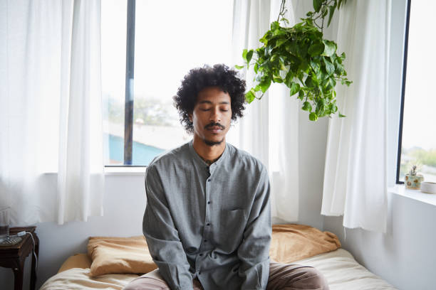 istock Young man sitting on his bed and meditating with his eyes closed 1270418885