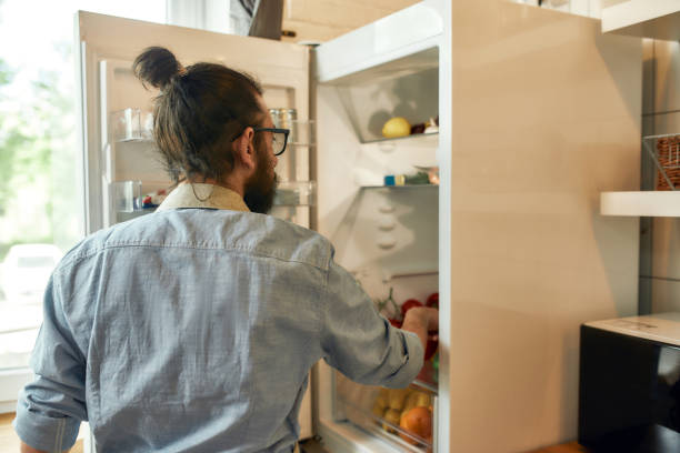 istock Young man, professional cook in apron taking ingredients out of the fridge while getting ready to prepare a meal, standing in the kitchen. Cooking at home concept 1270420380