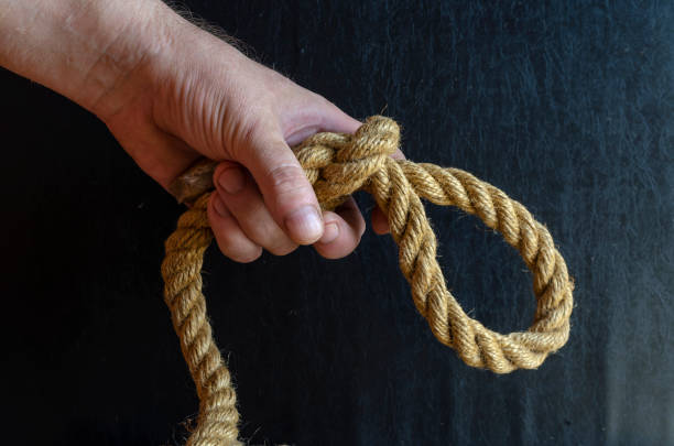 istock A man's hand holds a rope with a knotted knot on a dark background. 1270420814
