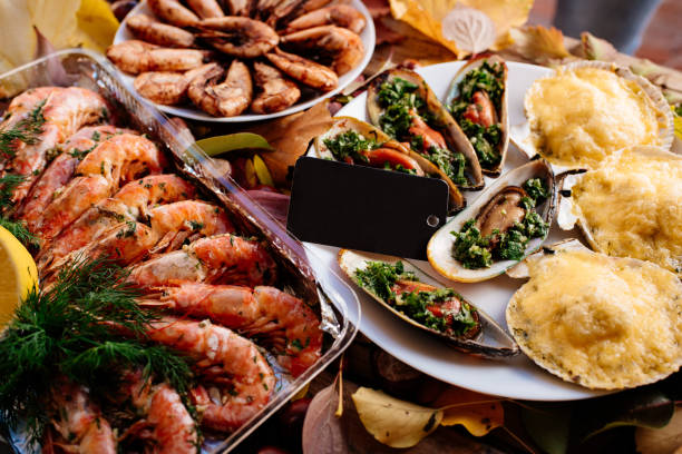 Shrimps, mussels and scallops on wooden table Fried shrimps, baked mussels and scallops baked under cheese on wooden table with autumn leaves and chestnuts. food state preparation shrimp prepared shrimp stock pictures, royalty-free photos & images