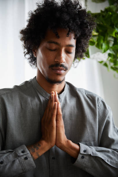 istock Young man with his hands clasped meditating alone at home 1270422160