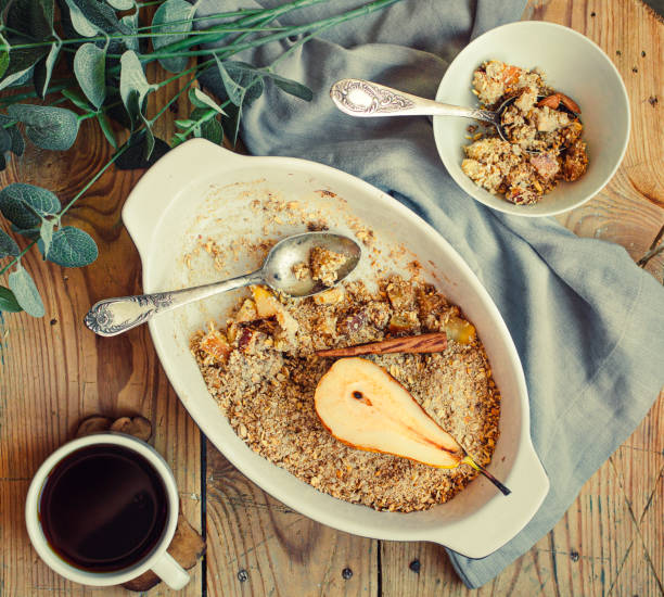 fruits and nuts crumble pie server in a glass bowl and cup of black tea or coffee on a wooden table. healthy dessert or morning breakfast concept. top view. - crumble imagens e fotografias de stock
