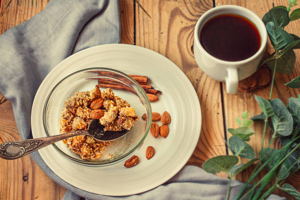 Fruits and nuts crumble pie server in a glass bowl and cup of black tea or coffee on a wooden table. Healthy dessert or morning breakfast concept. Top view.