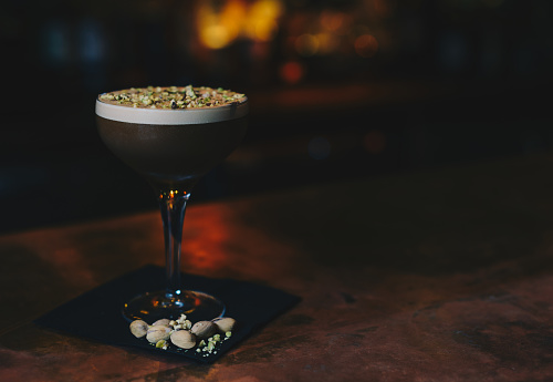 Espresso Martini cocktail with pistachio garnish, on copper bar top