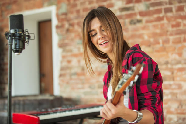 istock Woman in headphones recording music, singing or making broadcast internet tutorial while sitting in loft workplace or at home 1270426718