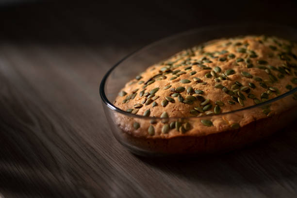 Homemade delicious pumpkin pie sprinkled with pumpkin seeds. It stands on a wooden table. Top view.