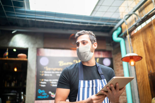 Waiter using digital tablet at restaurant wearing face mask
