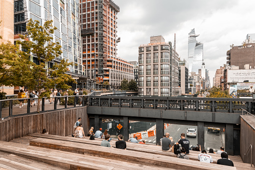 People sitting in the observation deck in the High Line Park in Manhattan. The urban park is popular by locals and tourists built on the elevated train tracks.