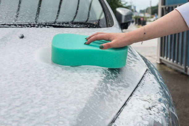 istock hand hold  sponge with white foam over the car for washing 1270430199