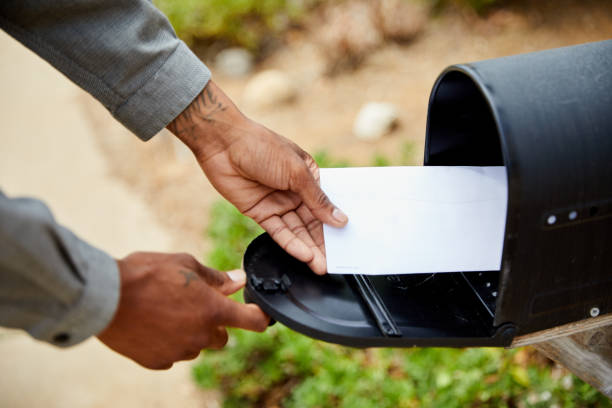 mężczyzna wyjmując kopertę ze swojej skrzynki pocztowej - mailbox zdjęcia i obrazy z banku zdjęć