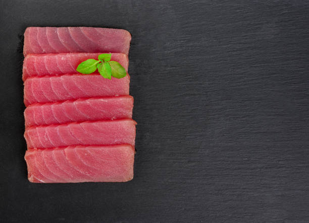 istock Fresh raw tuna steak with basil. On black rustic background 1270431775