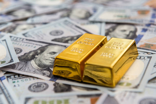 istock Expensive gold bar lying on dollar bills 1270431958