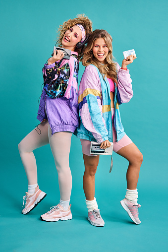 Studio shot of two beautiful young women styled in 80s clothing