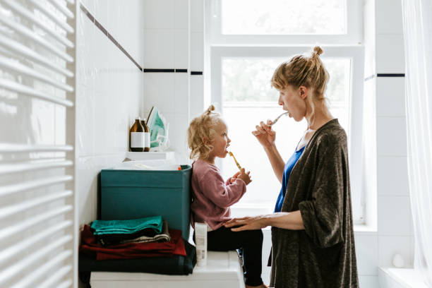 jonge moeder met een kind dat tanden in de ochtend borstelt - badkamer huis fotos stockfoto's en -beelden