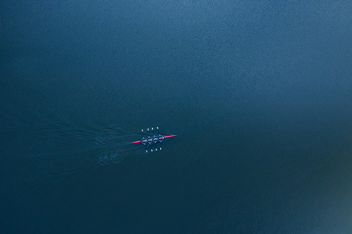 Boat coxed four rowers rowing on the blue river aerial view