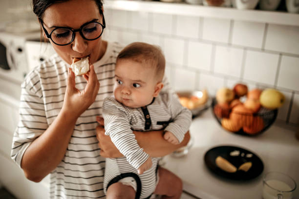 A young mother and her baby are sitting by the window in a cafe having lunch