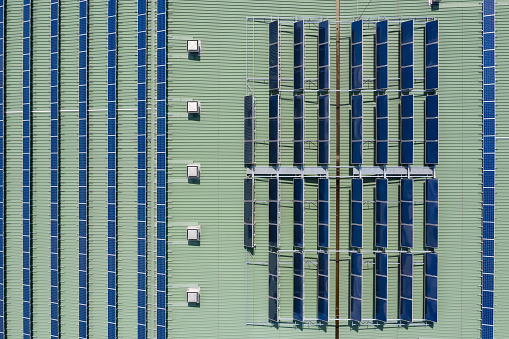 Solar panels and hot water heaters installed on the building roof, aerial drone top down view