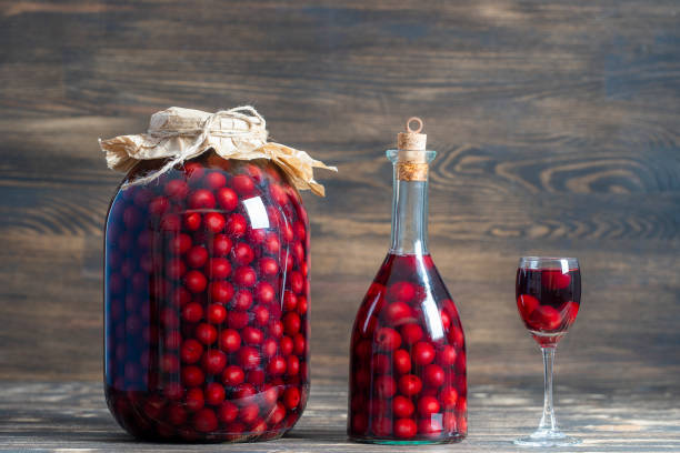 ガラス瓶、瓶、木製の背景にワイングラス、ウクライナ、クローズアップで赤い桜の自家製チンキ - whisky liqueur glass alcohol bottle ストックフォトと画像