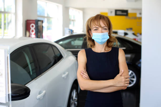 Car dealership during the pandemic Female saleswoman in a car dealership. About 40 years old, Caucasian blonde redhead. car rental covid stock pictures, royalty-free photos & images