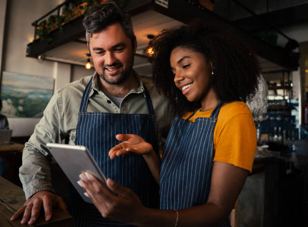 istock Smiling male and female colleagues discussing plans while looking at a tablet standing in coffee shop 1270455066