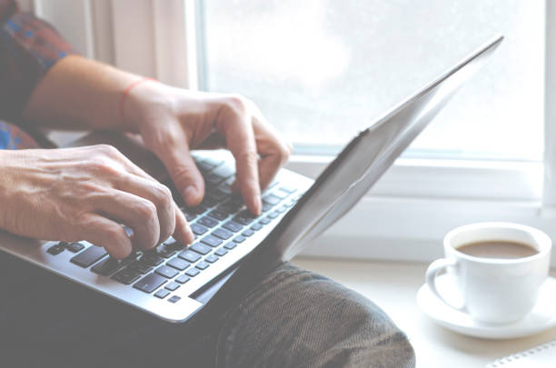 istock A man sits on a window sill with a laptop in his hands and works 1270455338