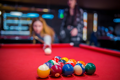 Young caucasian woman aiming at pool ball in an entertainment club