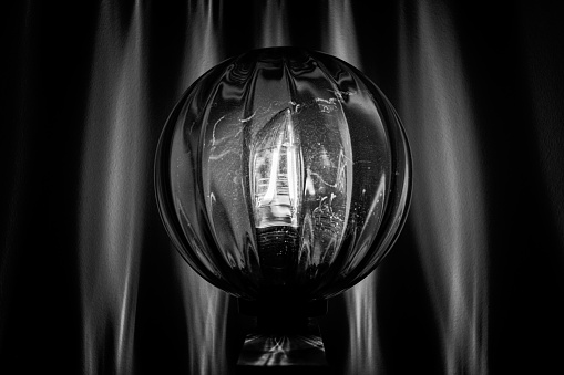 Interior design. Monochrome photo of lamp with round and clear sphere. Light reflection on the wall.