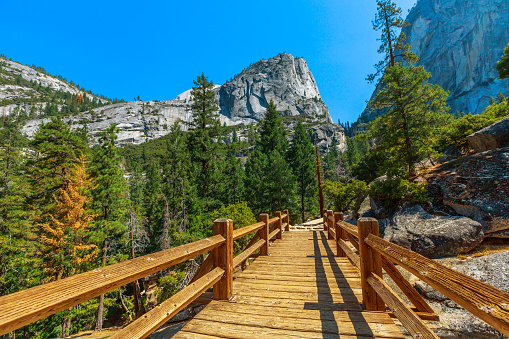 Panorama of Half Dome and Liberty Cap peaks of Nevada Fall waterfall on Merced River bridge of Mist trail in Yosemite National Park. Summer travel in California, United States.