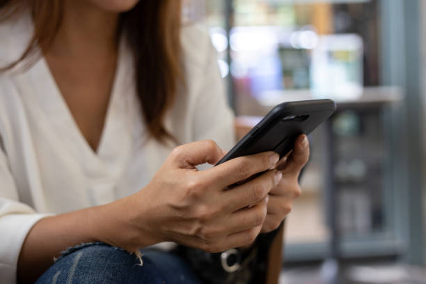 istock Asian Women sitting in a coffee shop using a smart phone for talking, reading and sending messages