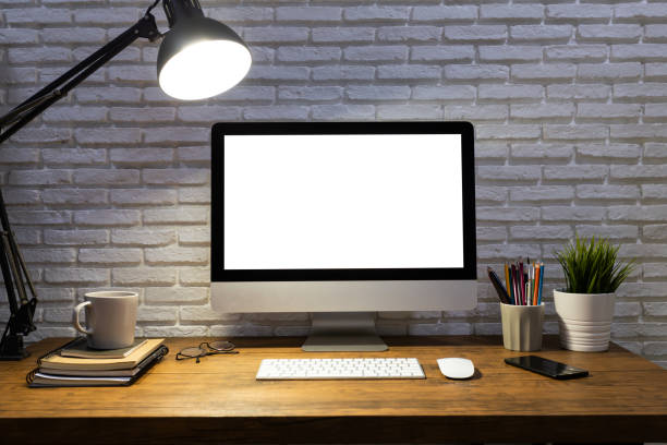 workspace with computer with blank white screen mockup, and office supplies on a wooden desk