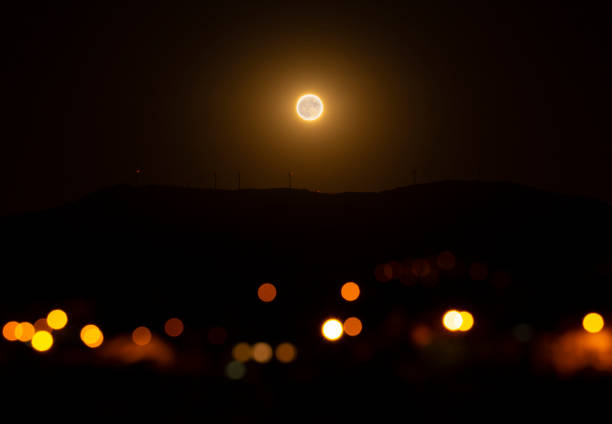 Orange full moon rising over the village mountain.