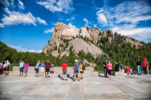 Keystone, United States - August 27, 2020:  Groups of tourists enjoying the view of Mount Rushmore National Memorial highlighted by the sculpture of four American presidents carved into the mountainside located in the Black Hills of Pennington County, South Dakota on a late summer morning.