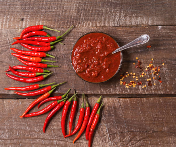 istock Hot chilli pepper sauce paste harissa, adjika ,chili pepper spices and fresh red chilli peppers, over wooden background. 1270471128