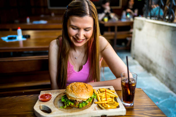 Young smiling woman looking at burger