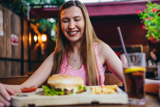 istock Young smiling woman looking at burger 1270476255