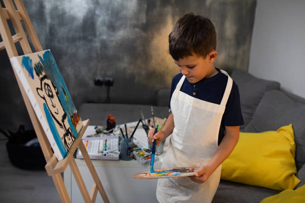 istock A cute boy applying colors to a brush while painting 1270476649