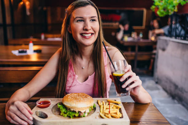 Woman eating burger in restaurant