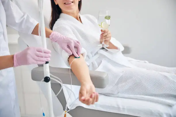 Photo of Smiling female patient undergoing intravenous vitamin therapy