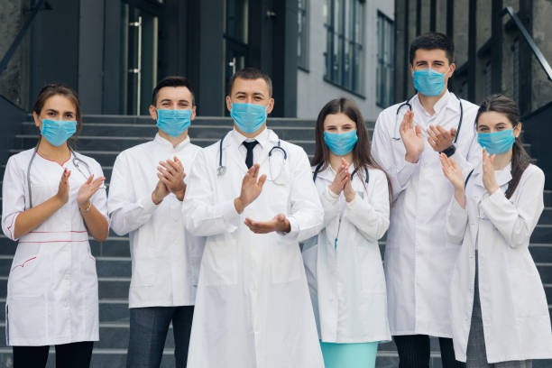 Medical staff from the hospital who are fighting coronavirus applaud back the people and police officers for their support. Group of doctors with face masks. Corona Virus and Healthcare Concept Medical staff from the hospital who are fighting coronavirus applaud back the people and police officers for their support. Group of doctors with face masks. Corona Virus and Healthcare Concept. civilian stock pictures, royalty-free photos & images