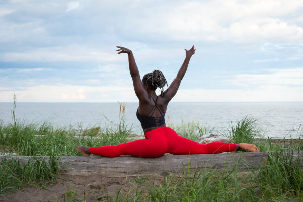 junge sportliche frau, die yoga am strand praktiziert - the splits flexibility yoga teenage girls stock-fotos und bilder