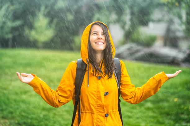 glückliches junges mädchen mit spaß unter dem regen - drenched raincoat rain clothing stock-fotos und bilder