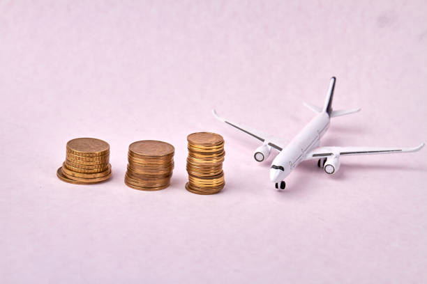 istock Rising stack of coins and toy model of a plane. 1270491691