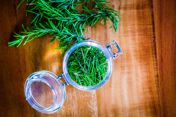 Dried rosemary as a spice in a glass on a rustic wooden table