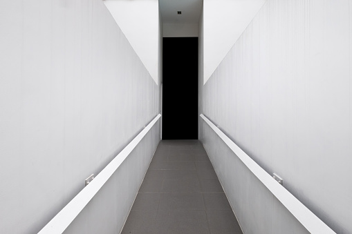 Concrete corridor with white wall and granite tile to black door