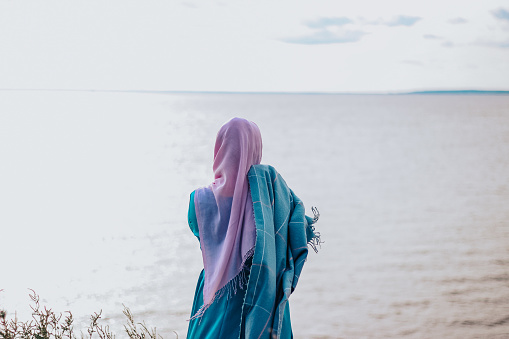 Muslim woman in a blue dress on the shore