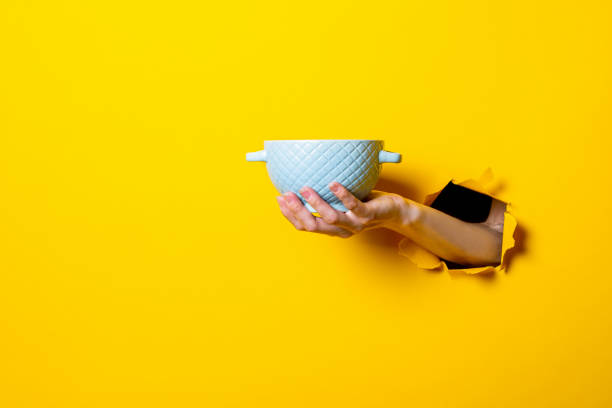 istock Female hand holding a blue bowl on a bright yellow background 1270500186